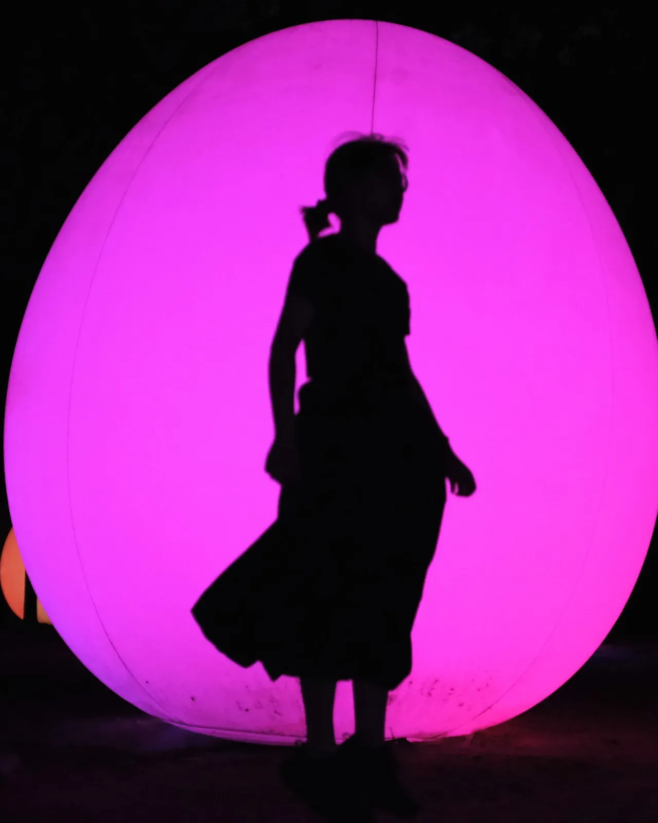 Silhouette of Cindy Young in front of a glowing magenta light installation
